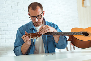 Checking the acoustic guitar string, repair of guitar pegs. Expert is tuning the guitar string,...