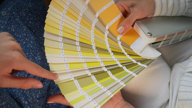 Young caucasian girl choosing paint color from swatch for new interior design. Close up palette