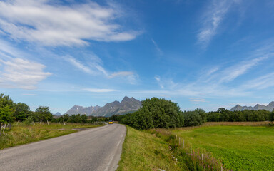 Fototapeta na wymiar road behind which you can see the impressive landscape with mountains and lake on a round trip on the lofoten islands in 