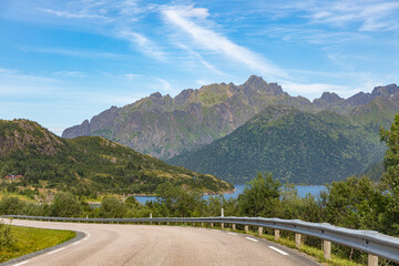 road behind which you can see the impressive landscape with mountains and lake on a round trip on the lofoten islands in 