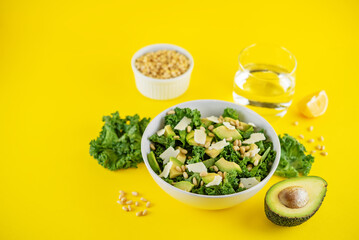 Kale avocado pine nuts cheese salad with lemon dressing in a bowl