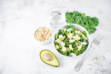 Kale avocado pine nuts cheese salad with lemon dressing in a bowl