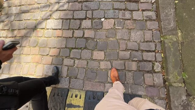 man and woman walking over cobblestone street in Paris