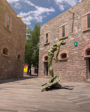 Outdoor secondary courtyard, stone architecture with statue at the center of a naked man looking up at the sky inside the Leonora Carrington Museum, no people