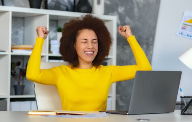 Happy excited young woman employee or office worker winner looking at laptop screen raised her...