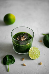 Green smoothie with spinach, banana, lime, chia seeds and pine nuts in a glass. Raw, vegan, vegetarian, healthy food concept