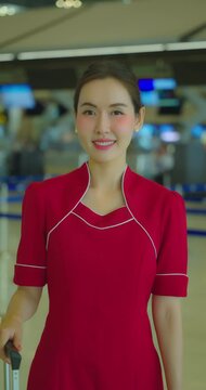 Portrait of flight attendant standing in airport terminal and smile to camera.