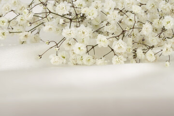 Soft focus smoke Gypsophila flower bouquet on white silk beige background.