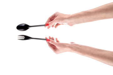Black plastic fork and spoon in female hands isolated on white background