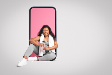 Positive plus size black woman with towel and bottle of water sitting in phone screen, grey background, free space