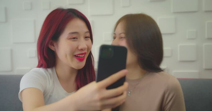 Young asian woman using phone to live streaming with friend in room. She using video call to talk with friend.