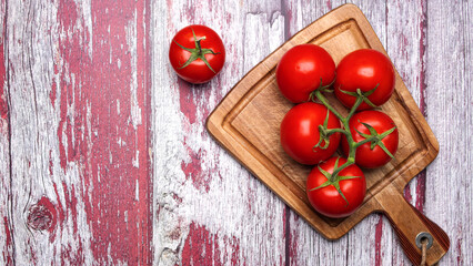 Ripe, juicy tomatoes in a bunch on a cutting board. Top view, space for text