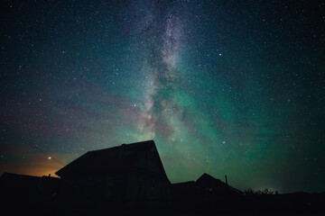 Stars sky and milky way above roofs in countryside