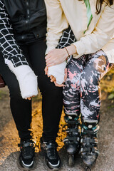A caring mother, a girlfriend in roller skates, holds her hands in a cast, a girl, a child after a fracture from sports, motivating after rehabilitation, sitting on a bench. Photography, portrait.