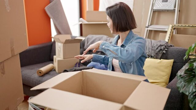 Young caucasian woman smiling confident packing cardboard box at new home
