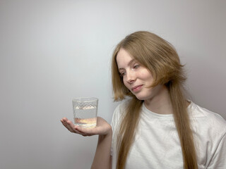 a young girl holds a glass of water in the palm of her hand