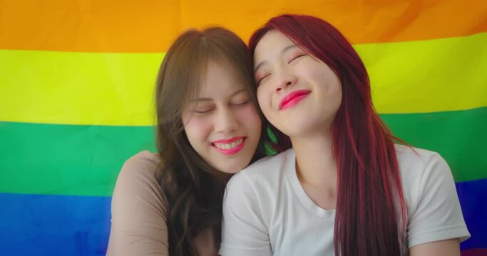 Portrait of a beautiful young lesbian couple smiling at LGBT flags.