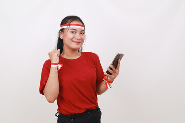 Young indonesian girl celebrate independence day while holding cell phone and clenched hand