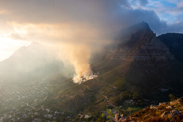 Smoke from a controlled burn at the foot of Table Mountain in Cape Town at sunrise, South Africa