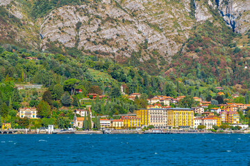 View from the lake of the colorful village of Cadenabbia, Italy, on the shores of Lake Como, with church, town, villas and ferry port in view.	