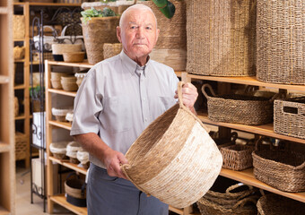 Adult man pensioner choosing storage basket at store of household goods