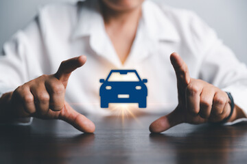 Business woman's hand protecting blue icon car on desk. Planning to manage transportation finance costs. Concept of car insurance business, saving buy - sale with tax and loan for new car.