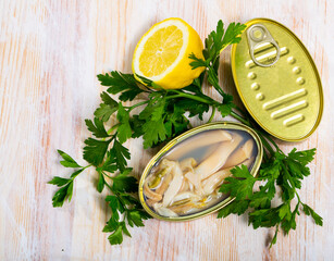 Image of tasty sea natural navajas in open tin can with lemon and greens