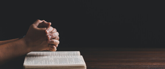 Hands folded in prayer on a Holy Bible in church concept for faith. banner with copy space