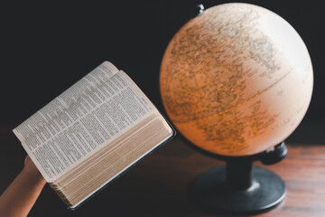 Christian woman praying for globe and people around the world on wooden table with bible. Christian...