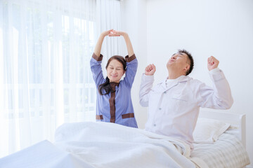 Obraz premium ベッドでストレッチをするシニア夫婦