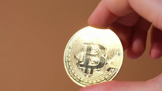 Female hands holding Bitcoin gold coin. Bitcoin mining trading concept. BTC golden money spinning around. Worldwide virtual internet Cryptocurrency or crypto digital payment system. Digital coin money