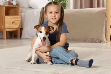 Cute girl with her dog on floor at home. Adorable pet