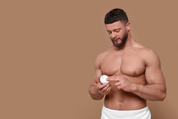 Fototapeta premium Handsome man applying body cream on pale brown background, space for text