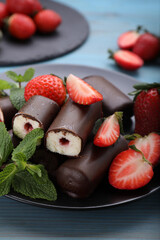 Delicious glazed curd snacks with fresh strawberries and mint on light blue wooden table