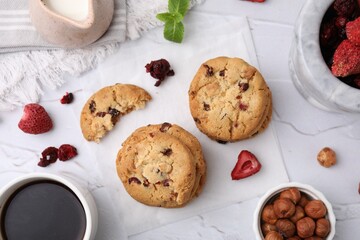 Cookies with freeze dried fruits, mint, milk, coffee and nuts on white textured table, flat lay