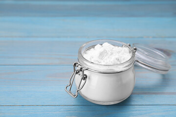 Glass jar of natural starch on light blue wooden table, closeup. Space for text