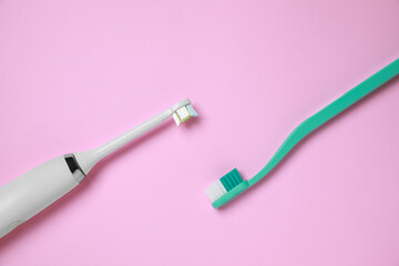 Electric and plastic toothbrushes on pink background, flat lay