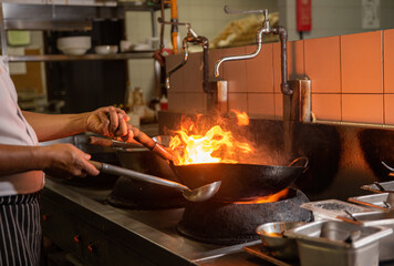 cooking doing flambe on pan in restaurant kitchen