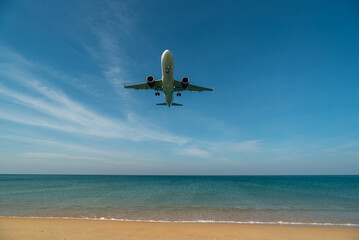 Fototapeta na wymiar Airplane will landing near blue beach.