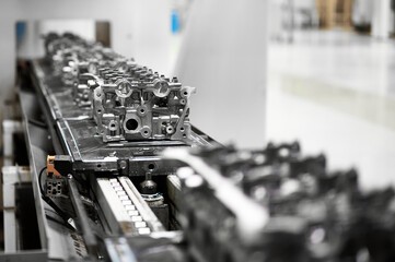 Car engine cylinder heads in housings on conveyor in shop