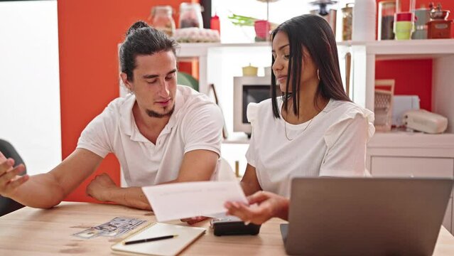 Man and woman couple using laptop accounting with worried expression at dinning room