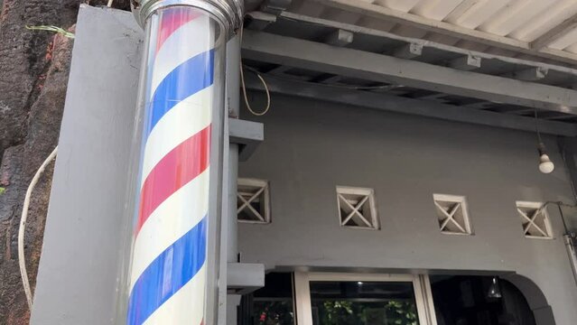 A barber pole spinning outside the barbershop on the street.