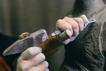Person holding gray metal sculpting tool