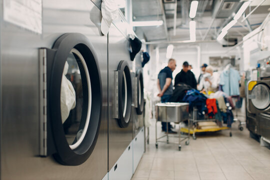 People next to washing machines doing laundry
