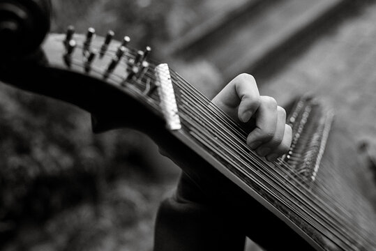 Person playing guitar in greyscale