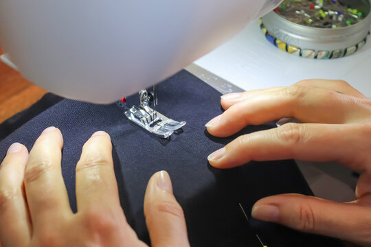 Person using sewing machine with some fabrics and textiles