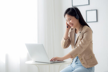Young asian businesswoman wearing headset video call and explain conference online at home, woman wearing headphone meeting and talking for working from home, business and communication concept.