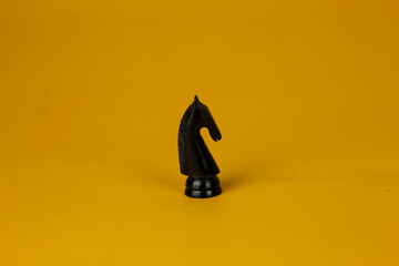 A black horse Chess standing for facing to problem on business on  isolated yellow background, used...