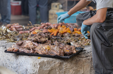 A man sets aside and puts on a tray the meat prepared underground as a part of the curanto...