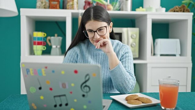 Young hispanic woman using laptop having breakfast at dinning room